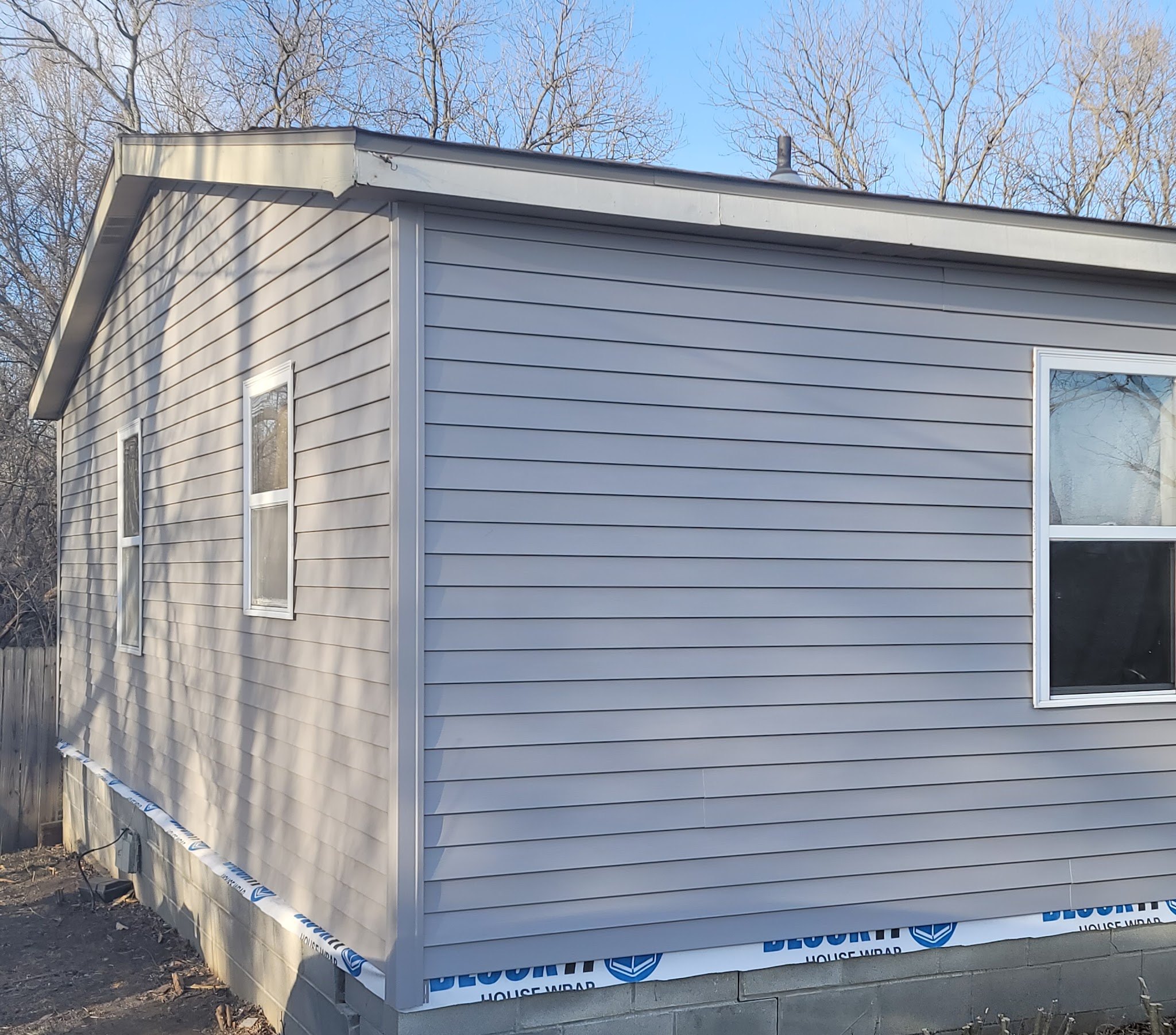 Home addition with new vinyl siding going on over house wrap